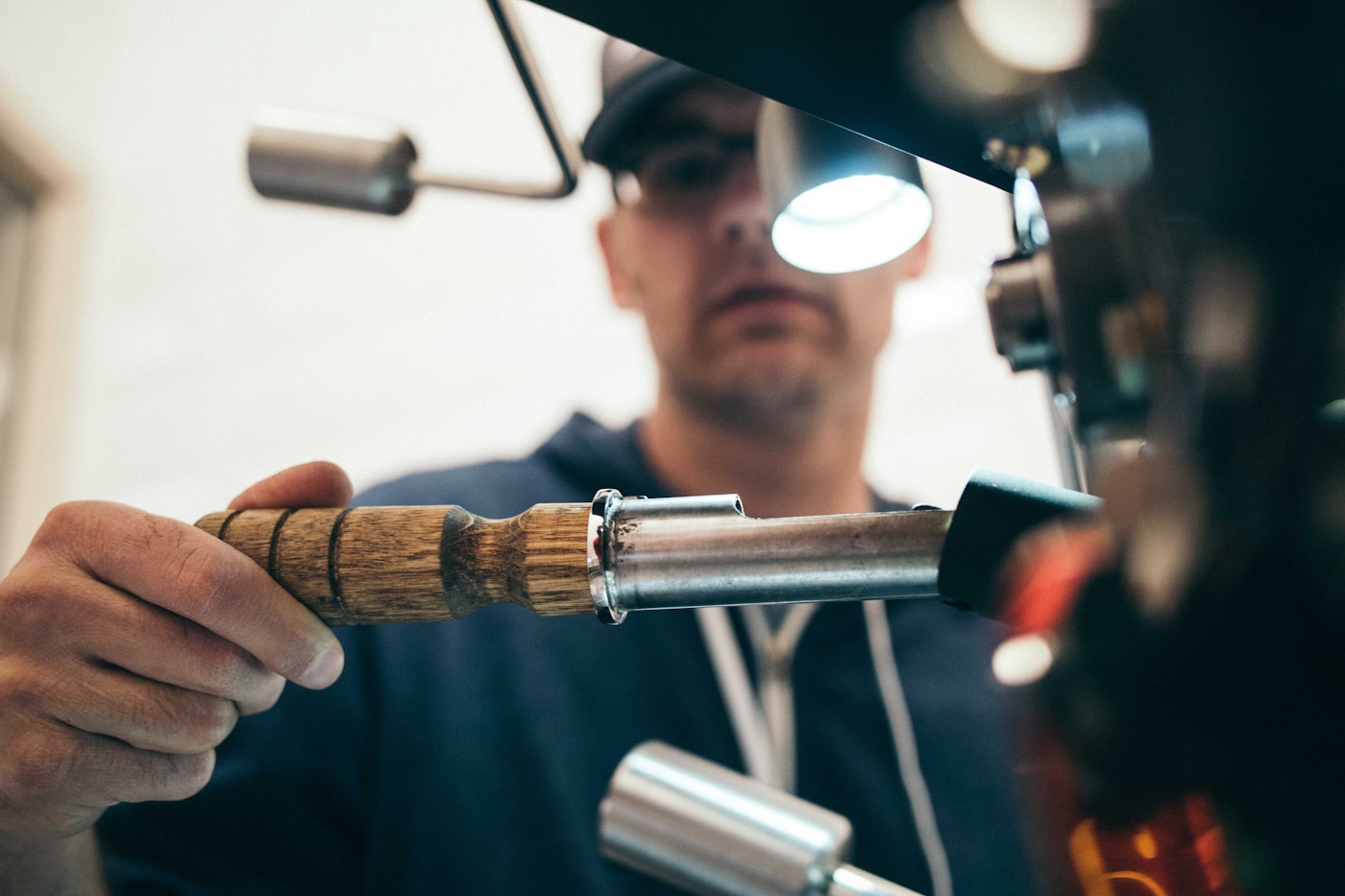Roaster pulling a sample from the drum with a trier
